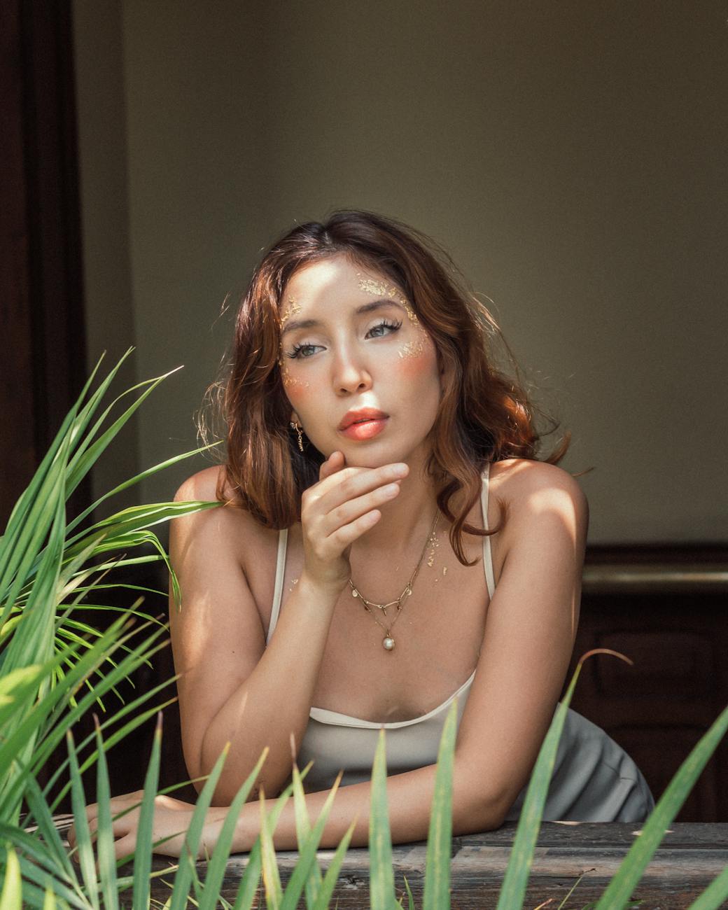 elegant woman influencer in jewelry posing surrounded by greenery